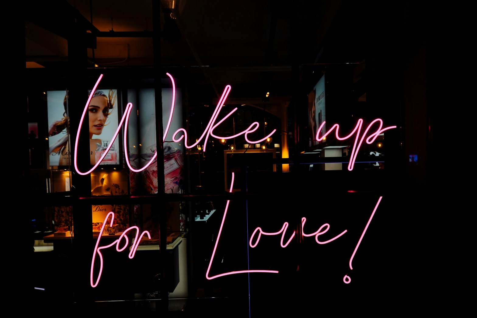 an image of a darkened cityscape with neon letters in the foreground spelling out "Wake up for Love!"